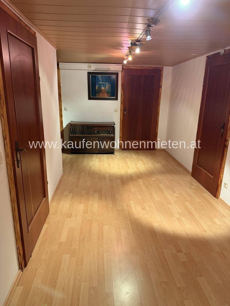 Langer Flur mit Laminatboden und Holzdecke, verbindet mehrere Zimmer im Haus.