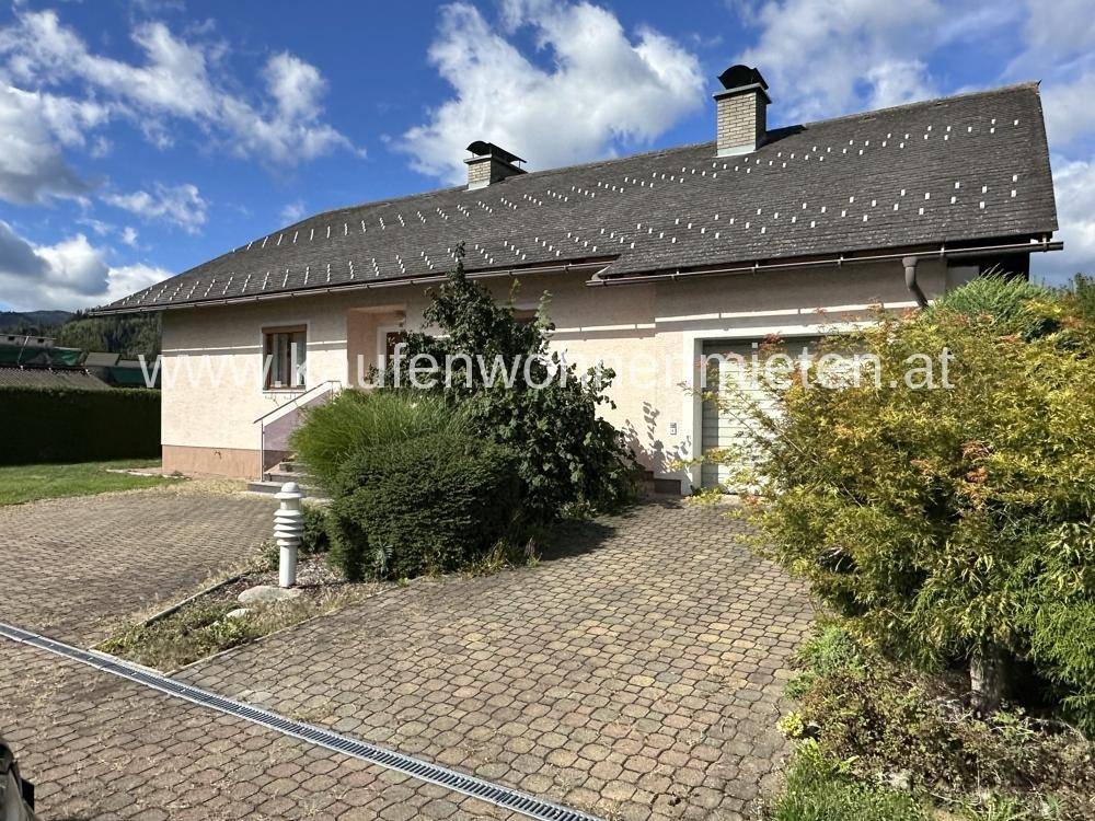 Ansicht des Einfamilienhauses von der Seite mit gepflasterter Zufahrt und Garten.