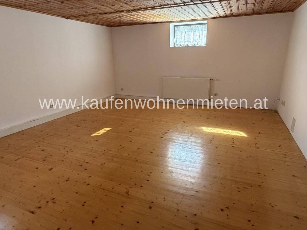 Geräumiger Raum mit Holzdielenboden und Holzdecke, ideal als Hobby- oder Abstellraum.