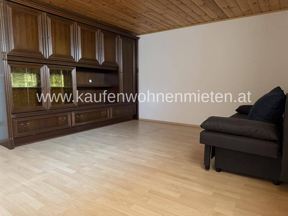 Wohnraum mit großem Holzschrank, Sofa und Laminatboden, bietet viel Stauraum.