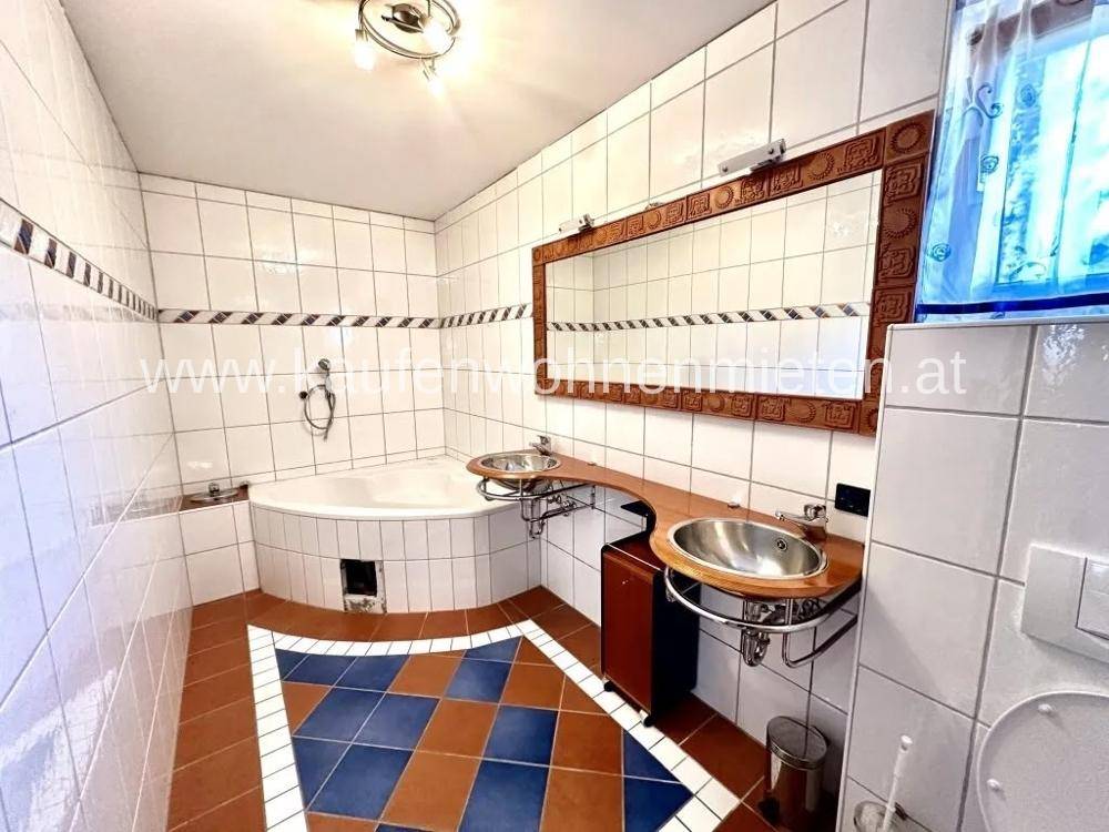 Geräumiges Badezimmer mit Eckbadewanne, Doppelwaschbecken und auffälligen Bodenfliesen.