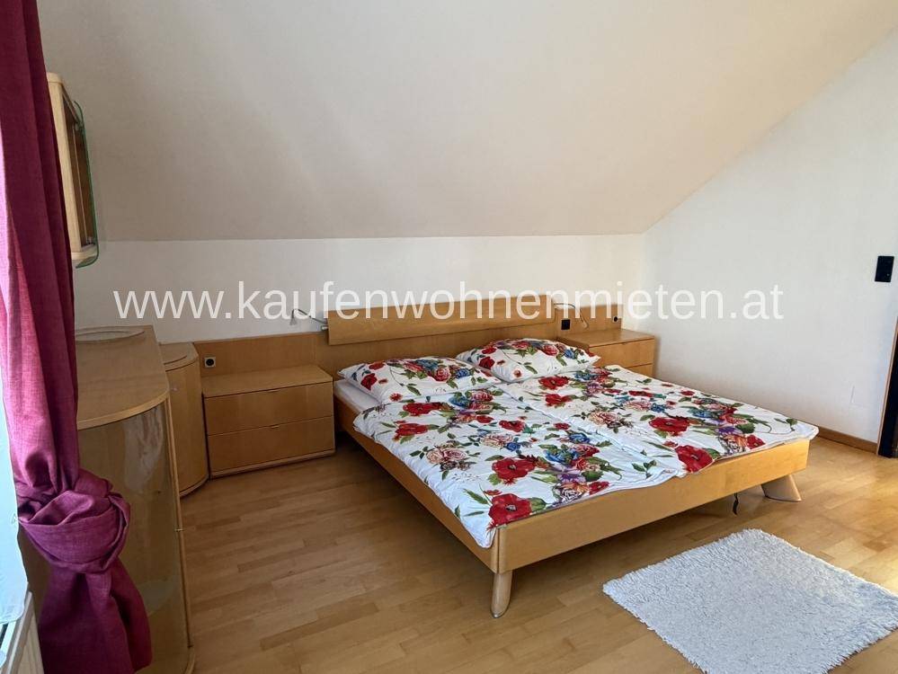 Helles Schlafzimmer mit Holzboden, Dachschräge und einem großen Doppelbett.