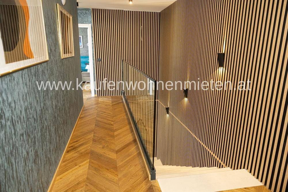 Moderner Flur mit Holzlamellenwand, Fischgrätparkett und eleganter Glasgeländer-Treppe.