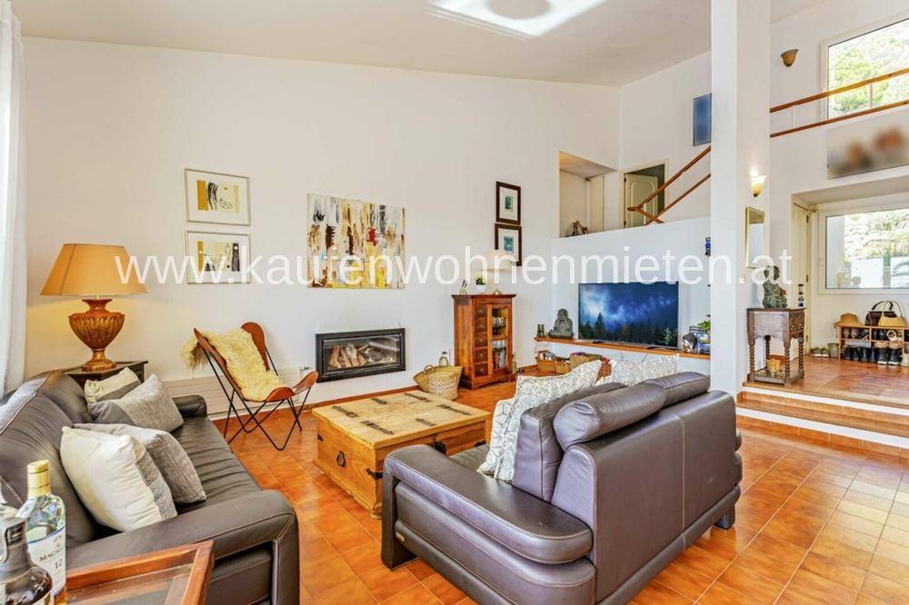 Geräumiges Wohnzimmer mit Kamin, Ledersofas und hohen Decken.