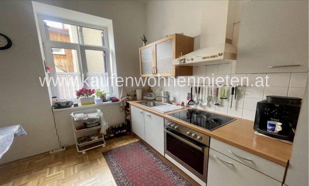 Funktionale Küche mit Holztheke, Einbaugeräten und Fenster mit Blick nach draußen.