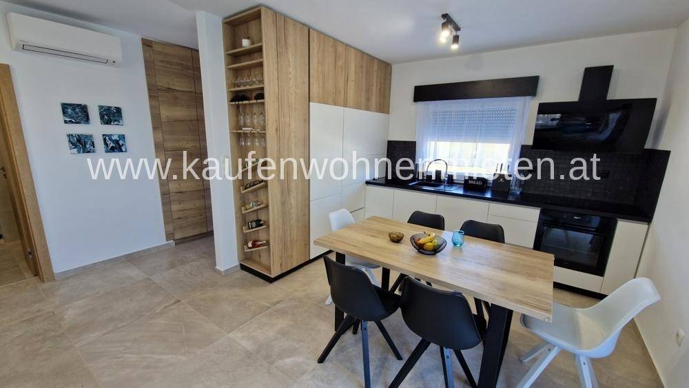 Moderne Einbauküche mit Holzakzenten, Essbereich und hochwertigen Geräten.