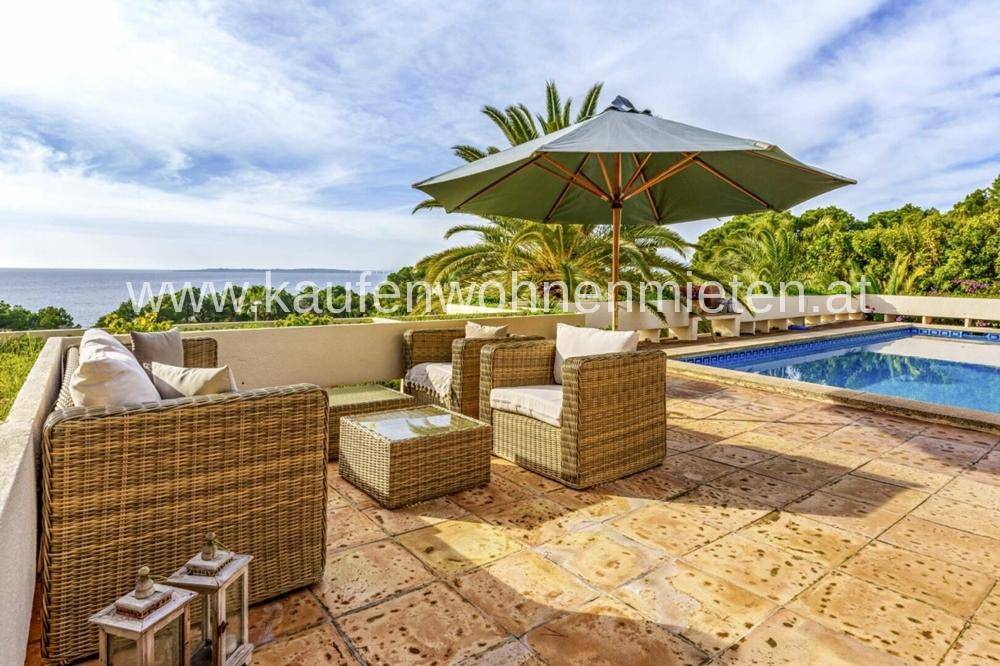 Geräumige Terrasse mit Rattanmöbeln, Sonnenschirm und weitem Meerblick.