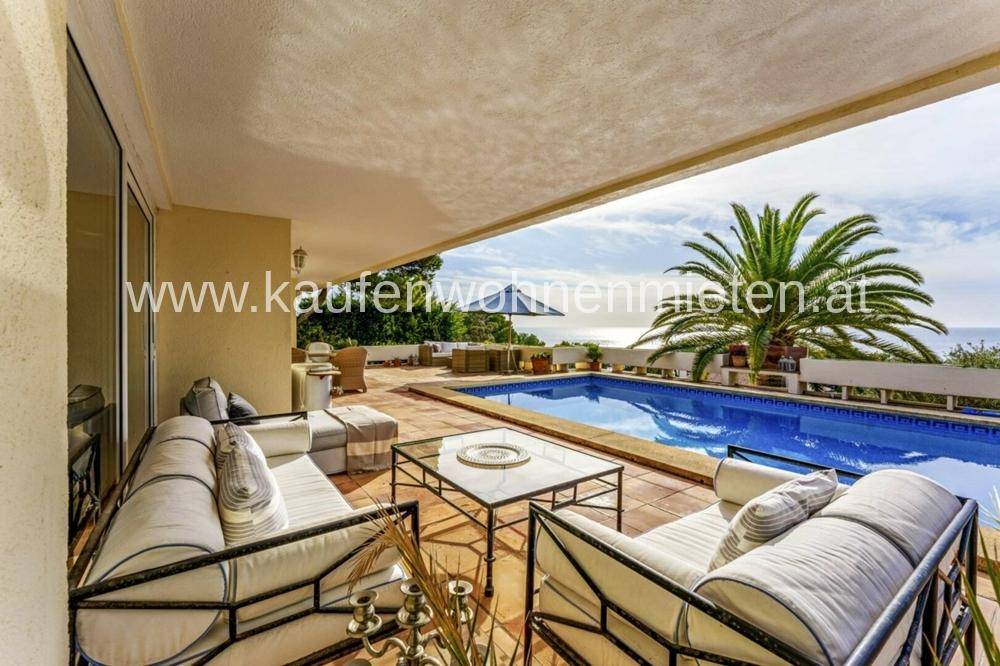 Überdachte Terrasse mit bequemen Lounge-Möbeln, Pool und Meerblick.
