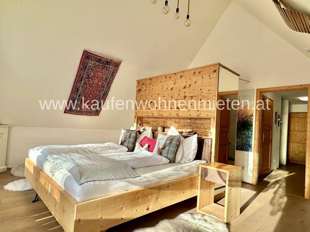 Helles Schlafzimmer mit großem Holzbett, Dachschräge und rustikalen Holzelementen.