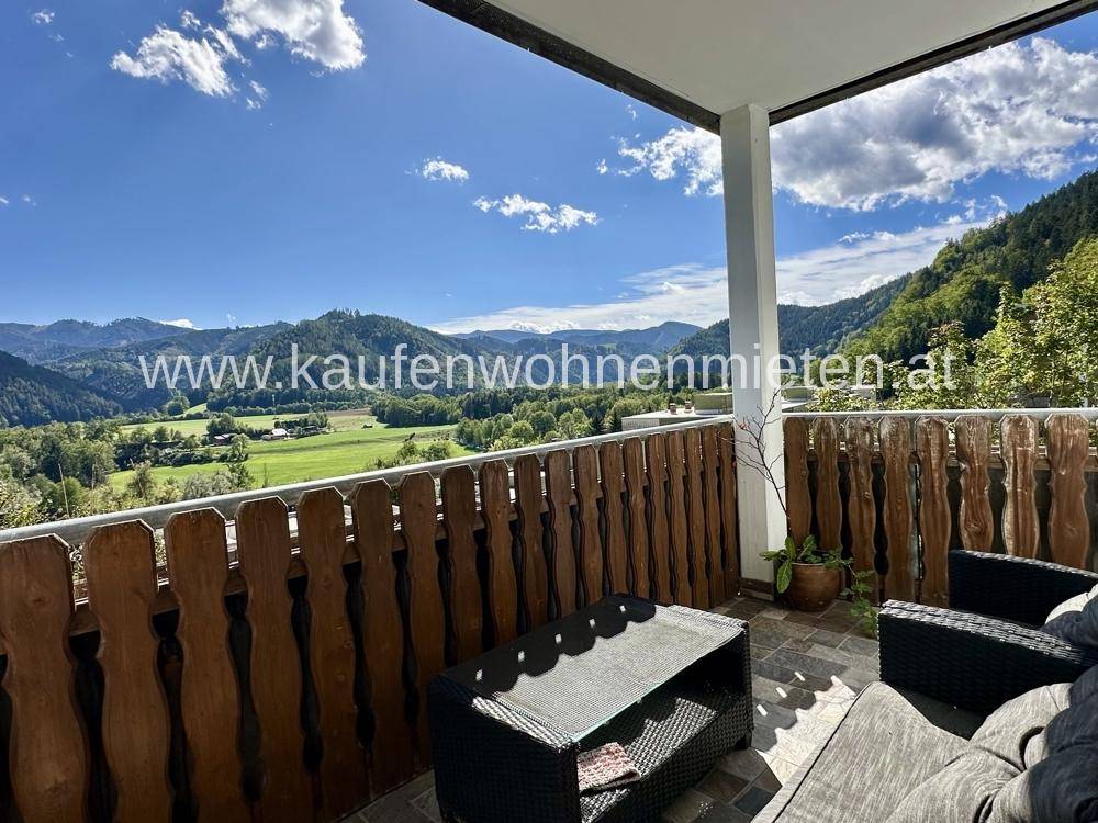 Möblierter Balkon mit rustikalem Holzgeländer und atemberaubendem Panoramablick auf die umliegende Bergwelt.