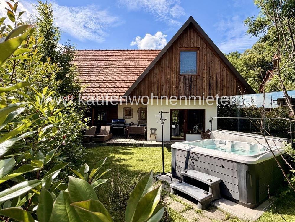 Gartenbereich mit Whirlpool, Terrasse und Sitzgelegenheiten vor dem Haus.