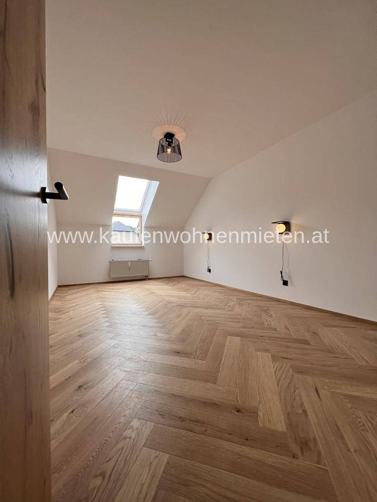 Helles Schlafzimmer im Dachgeschoss mit Dachschräge, Dachfenster und Fischgrätparkettboden.