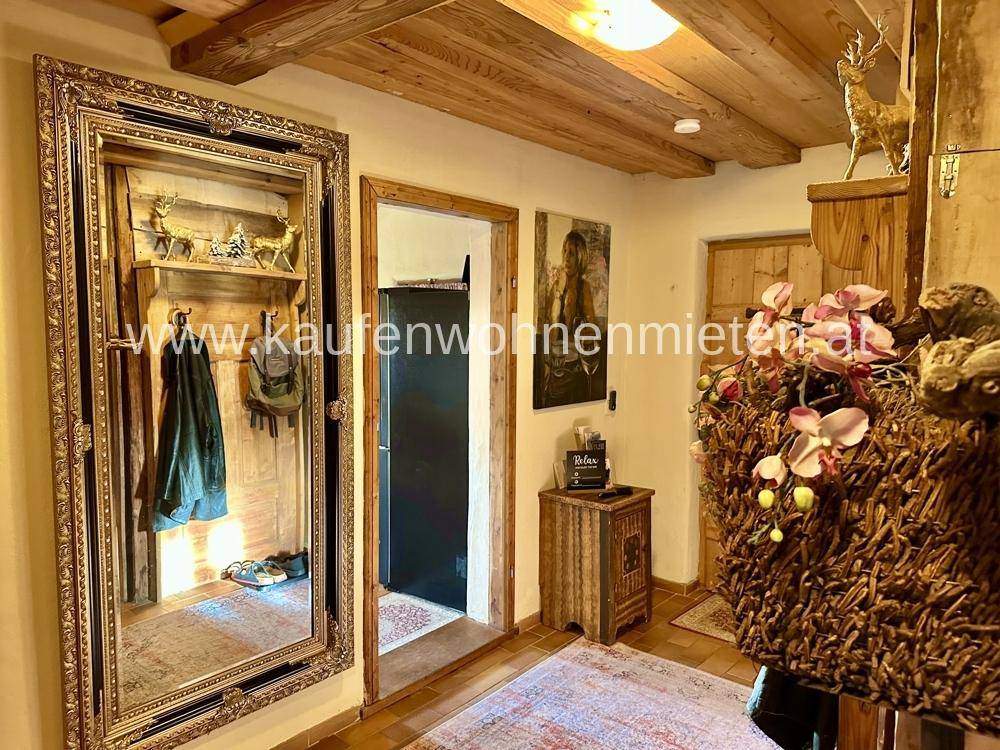 Eingangsbereich mit großem Spiegel, Holzbalkendecke und rustikaler Dekoration.