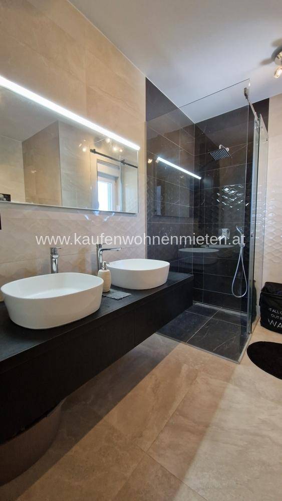 Modernes Badezimmer mit Doppelwaschbecken, großem Spiegel und begehbarer Dusche.