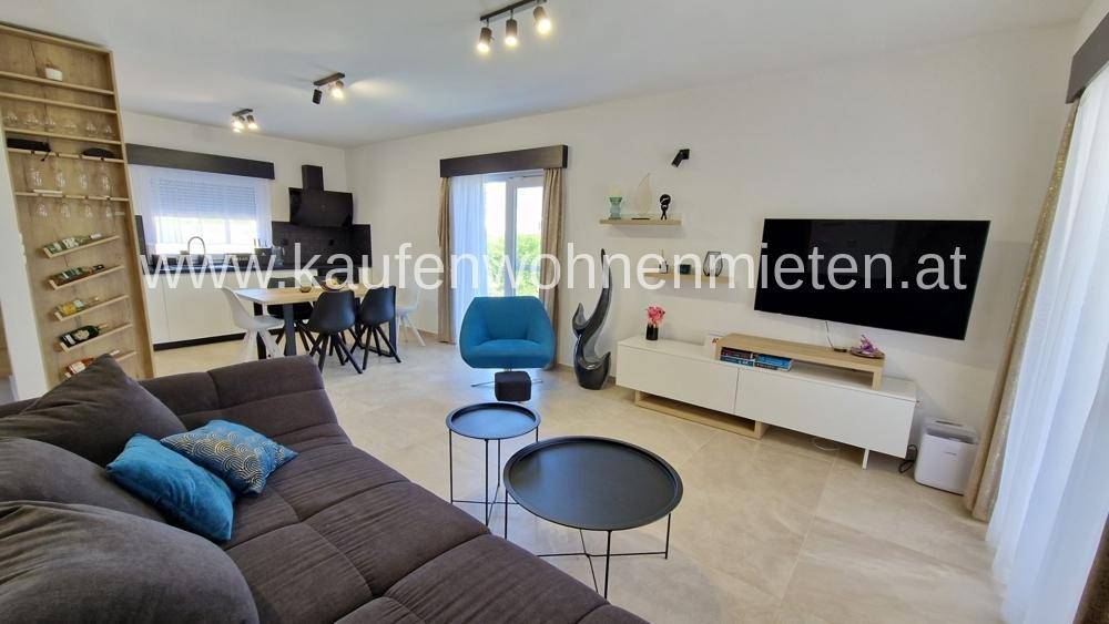 Heller offener Wohn-Essbereich mit modernem Sofa, Esstisch und integriertem Regal.