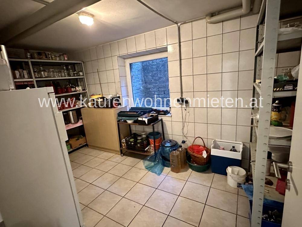 Abstellraum mit Fliesenboden, Regalen und einem Fenster.