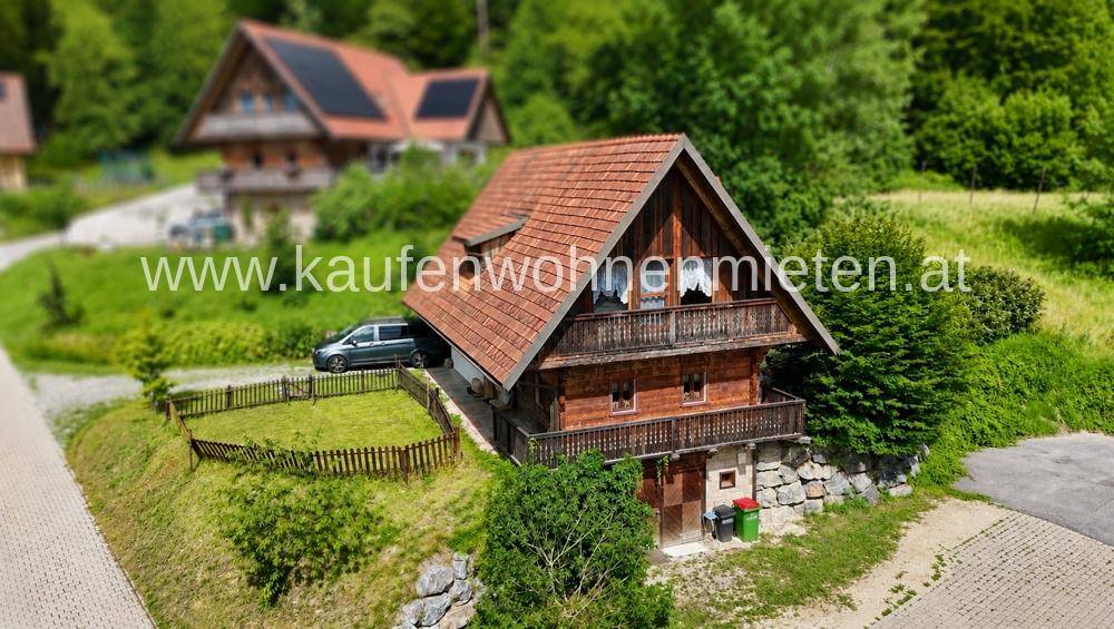 Traditionelles Holzhaus mit Ziegeldach und Balkonen, eingebettet in eine grüne Landschaft.
