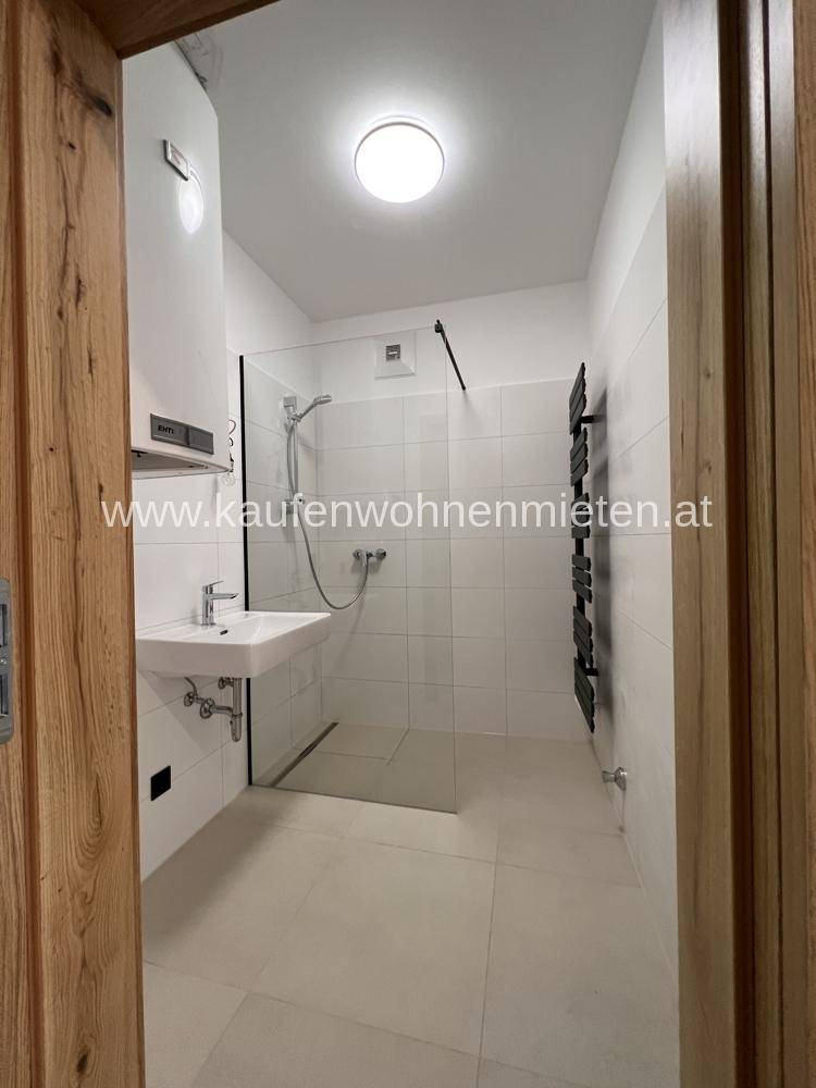 Modernes Badezimmer mit ebenerdiger Dusche, Einzelwaschbecken und beheiztem Handtuchhalter.