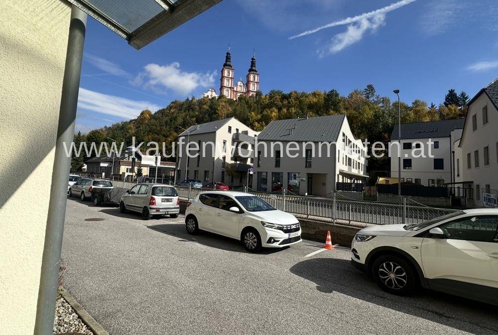 Straße mit geparkten Autos und Blick auf eine Kirche auf einem Hügel im Hintergrund.