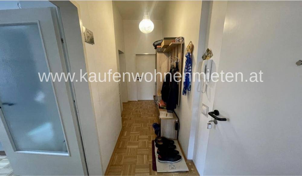 Heller Flur mit Parkettboden und Garderobe, der zu weiteren Räumen führt.