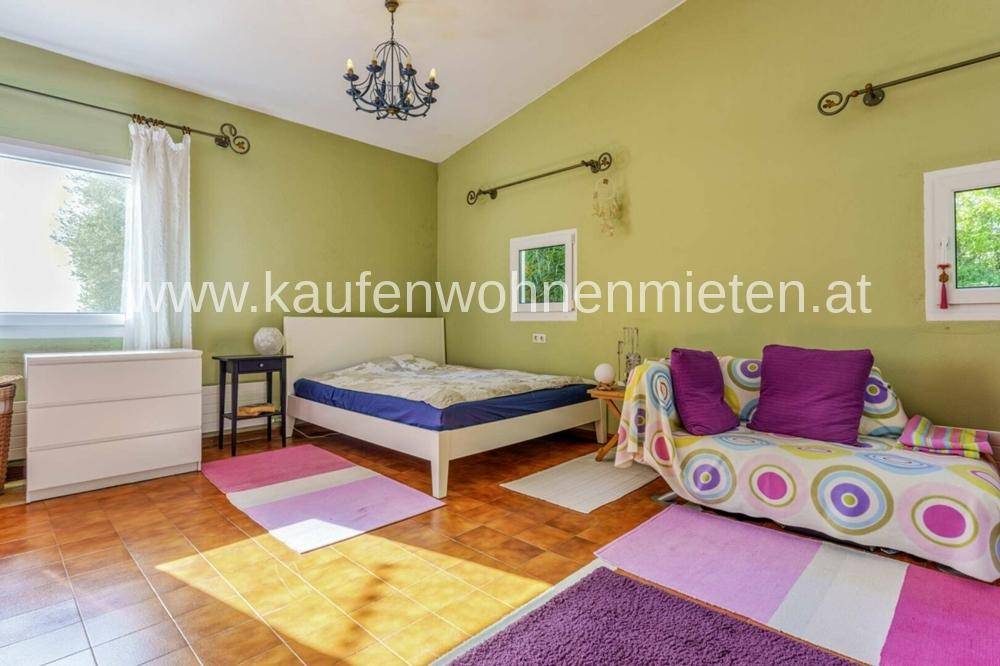 Schlafzimmer mit grünen Wänden, Holzboden und farbenfrohen Teppichen.