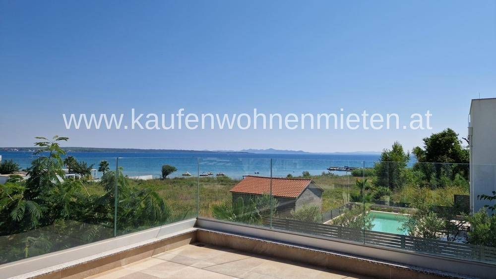 Große Dachterrasse mit Glasgeländer und atemberaubendem Blick auf das Meer und die Berge.