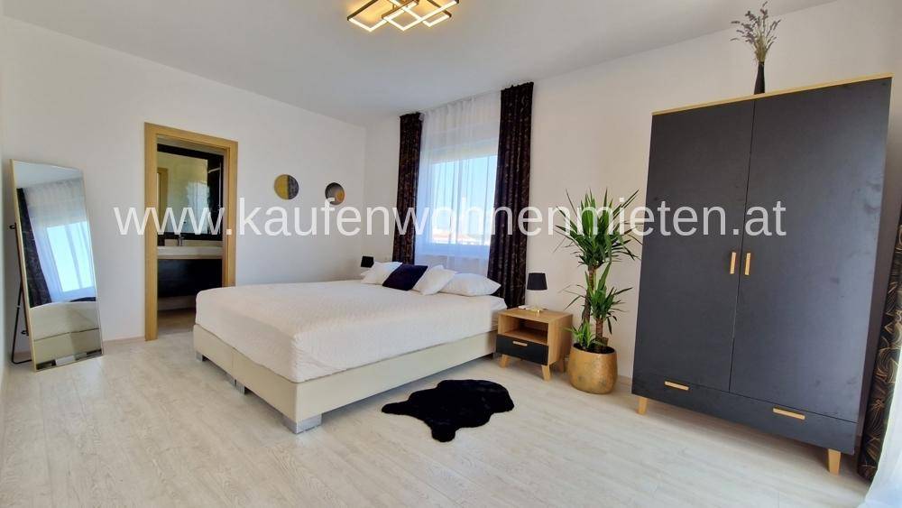 Helles Schlafzimmer mit Doppelbett, großem Kleiderschrank und Zugang zu einem eigenen Bad.