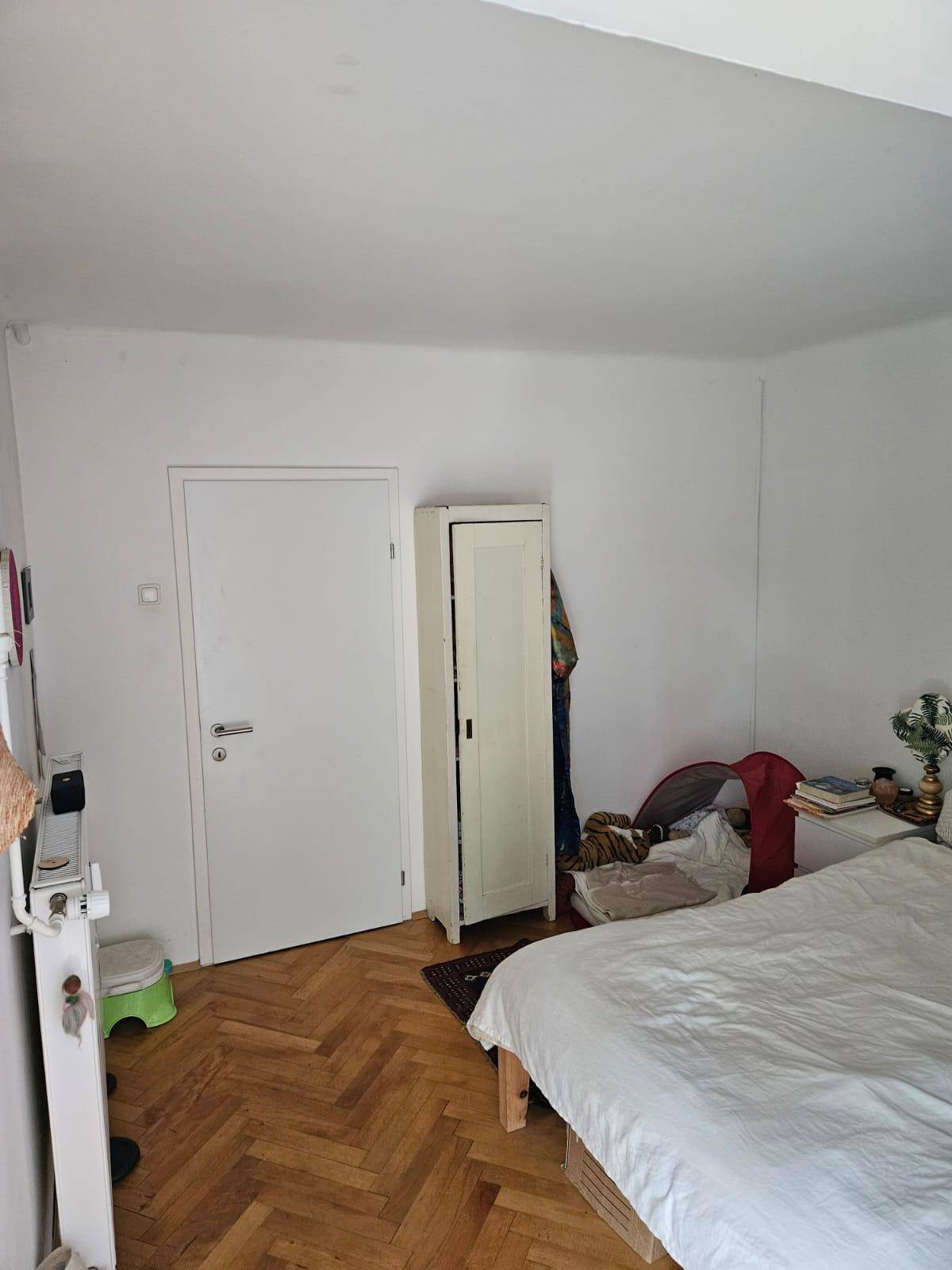 Schlafzimmer mit hellem Fischgrätparkett und weißer Wandfarbe.