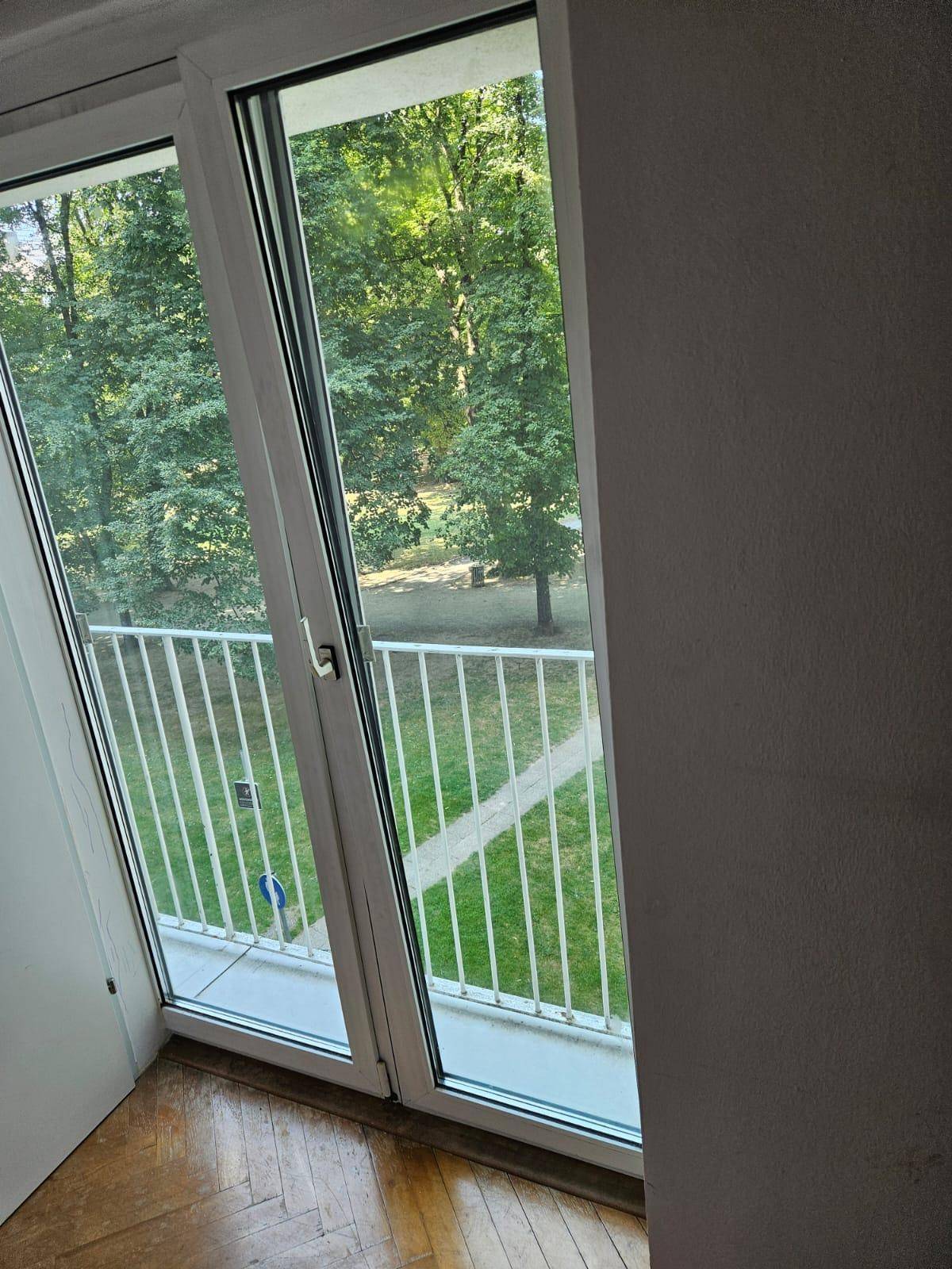 Fenster mit Blick auf grüne Bäume und Rasenfläche von einem Schlafzimmer aus.