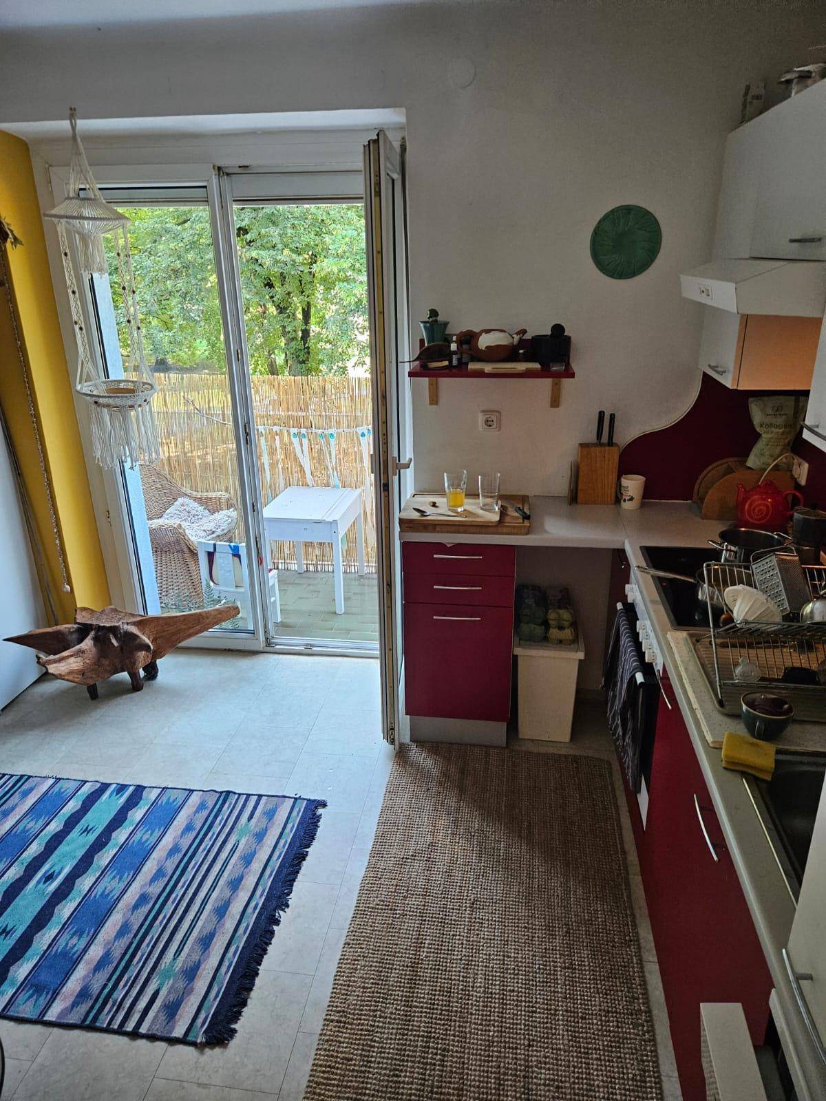 Helle Küche mit Zugang zum Balkon und Blick ins Grüne.
