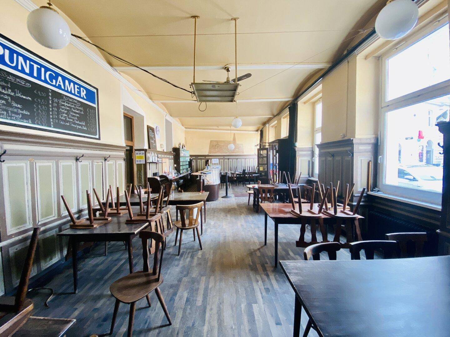 Langer Gastraum eines traditionellen Restaurants mit Holztäfelung, Holzböden und Tischen mit gestapelten Stühlen.