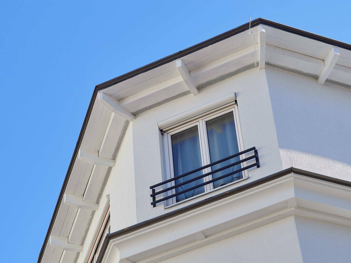Detailansicht eines Fensters mit französischem Balkon und weißer Fassade.