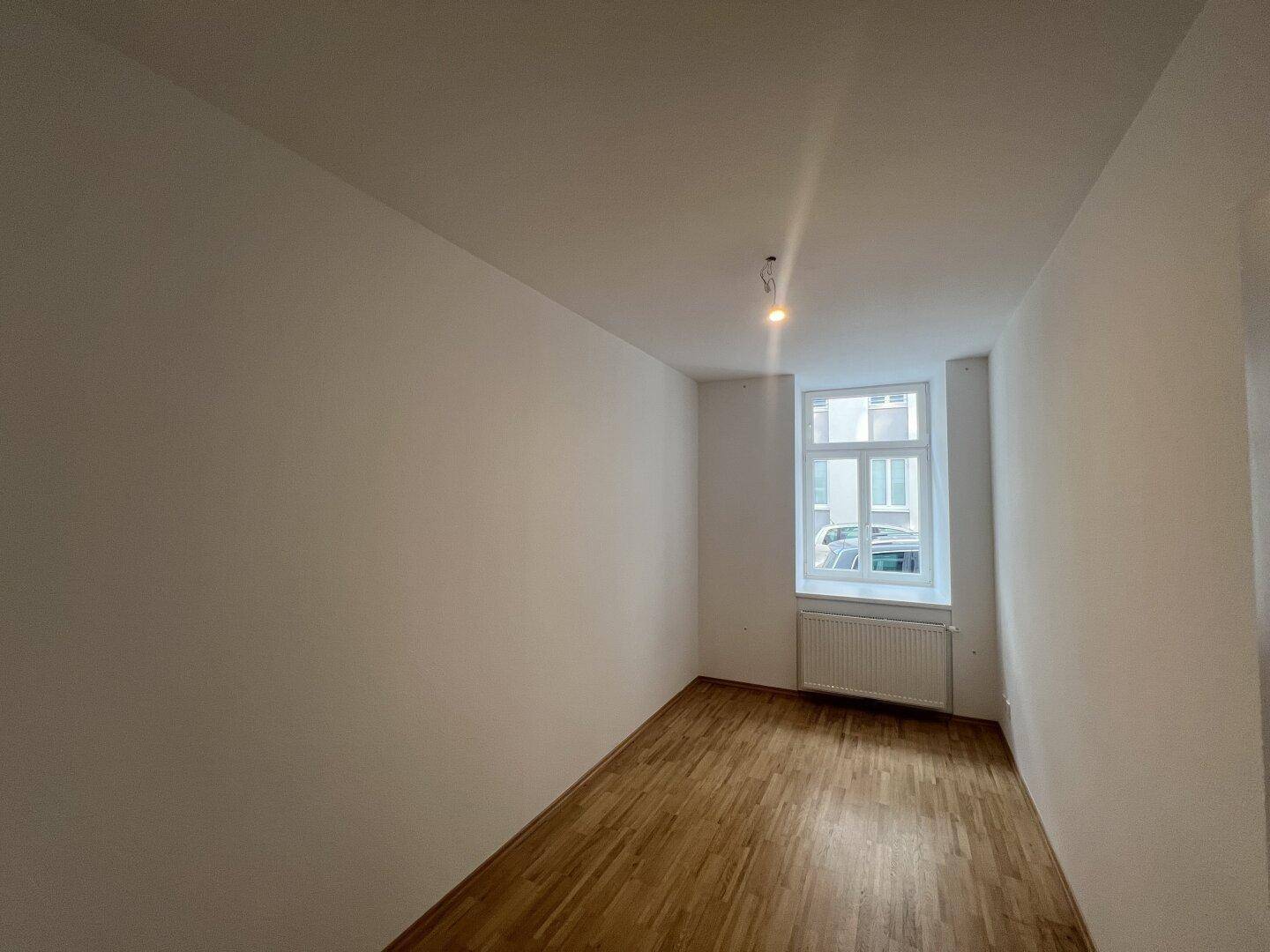 Gemütliches Zimmer mit Holzboden und einem Fenster, das für natürliches Licht sorgt.