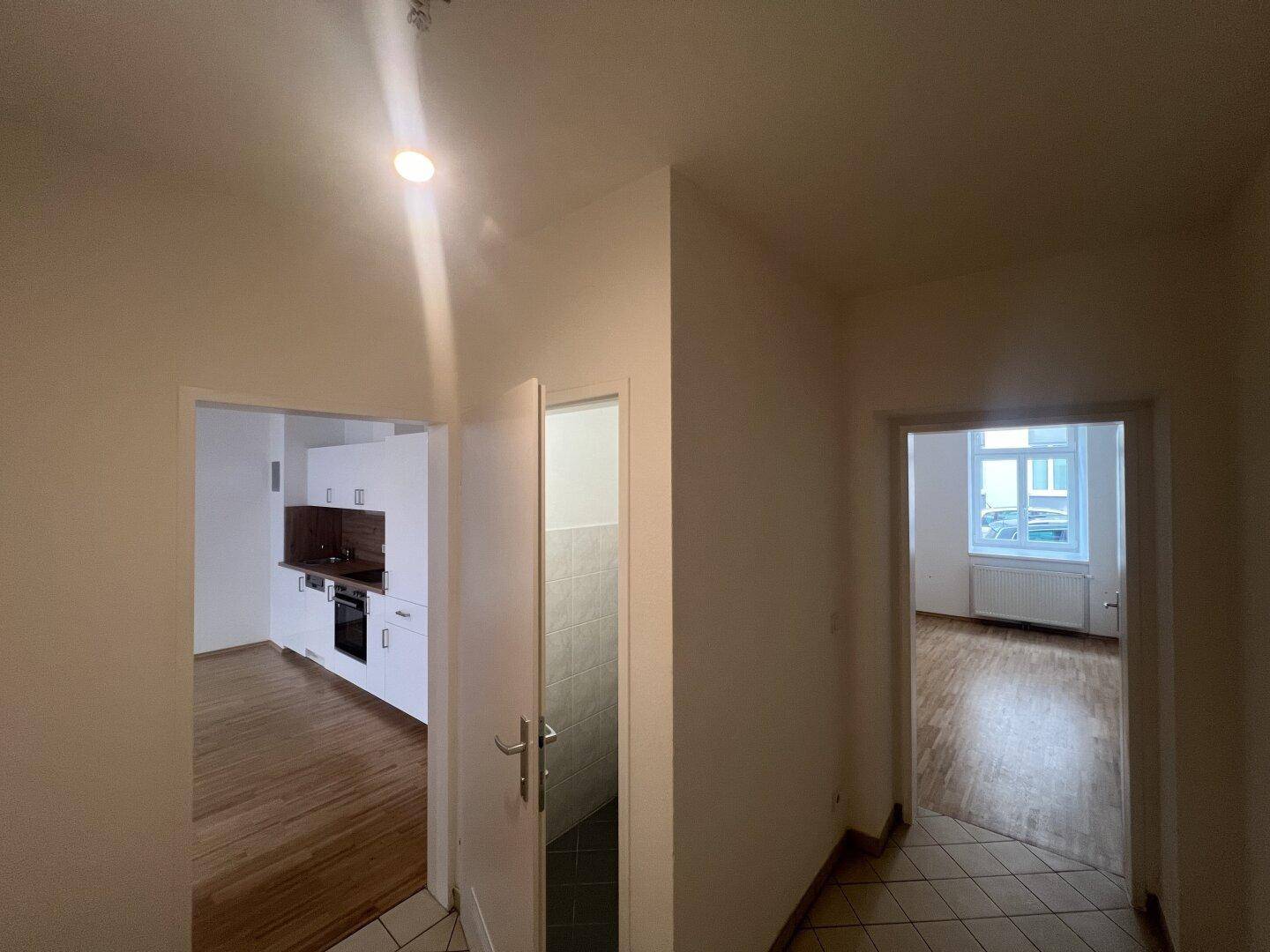 Heller Flur mit gemusterten Fliesen, der zu den verschiedenen Zimmern der Wohnung führt.