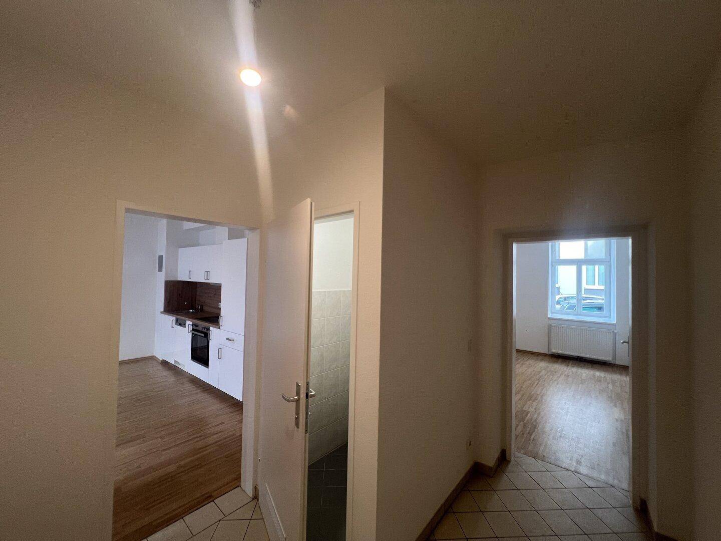 Heller Flur mit gemusterten Fliesen, der zu den verschiedenen Zimmern der Wohnung führt.