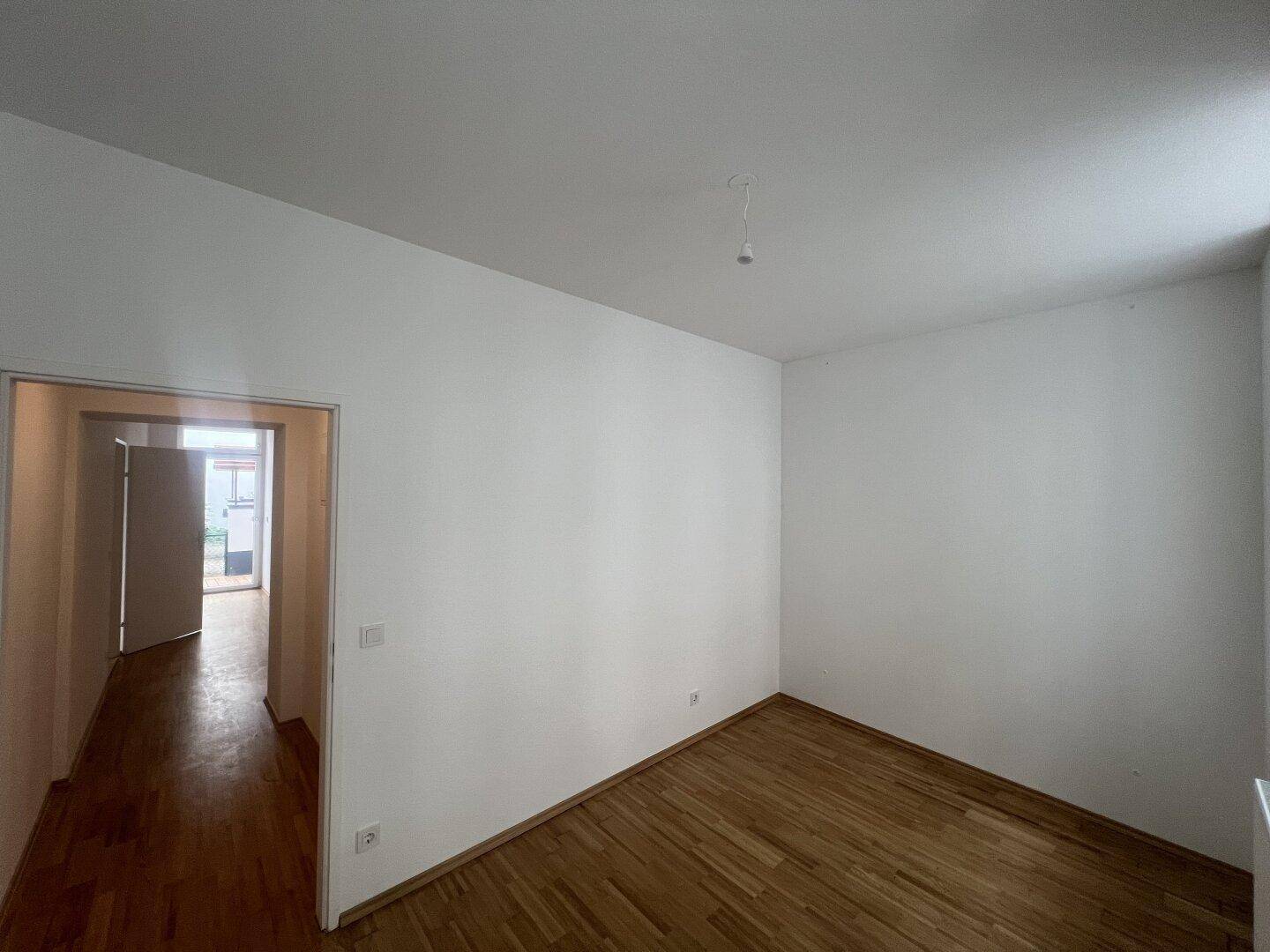 Heller Raum mit Holzboden und Zugang zu einem Außenbereich, ideal für entspannte Stunden.
