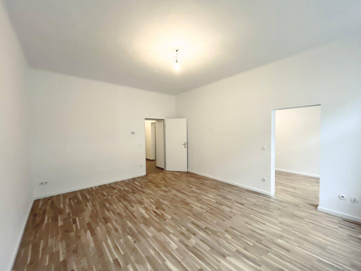 Leeres Zimmer mit Parkettboden und mehreren Türen, bietet flexible Raumgestaltungsmöglichkeiten.