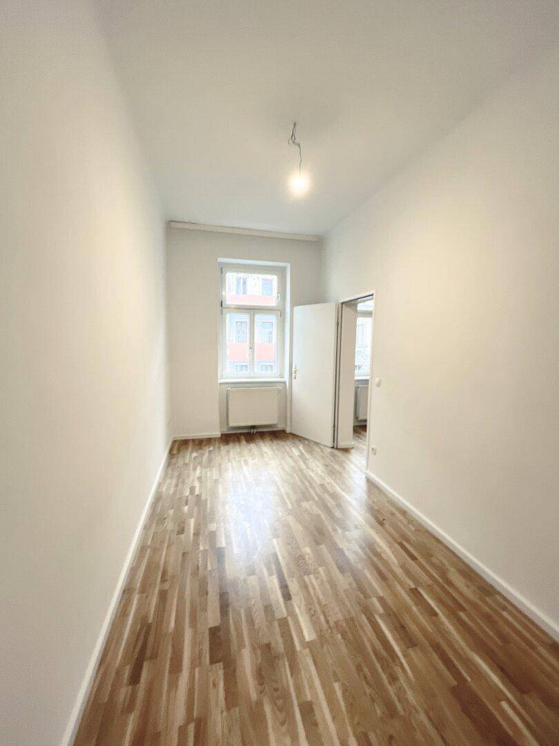 Schmaleres Zimmer mit Parkettboden und einem Fenster, geeignet als Schlaf- oder Arbeitszimmer.