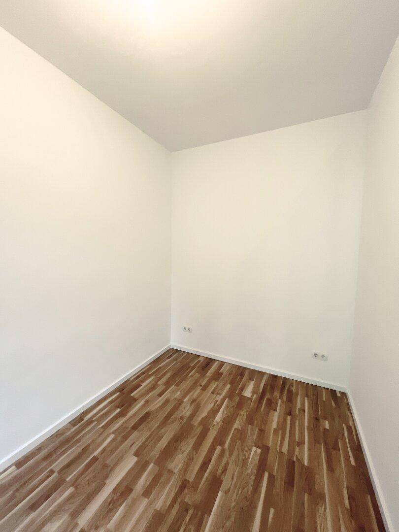 Leeres Zimmer mit Parkettboden und weißen Wänden, bietet eine neutrale Basis für Einrichtung.
