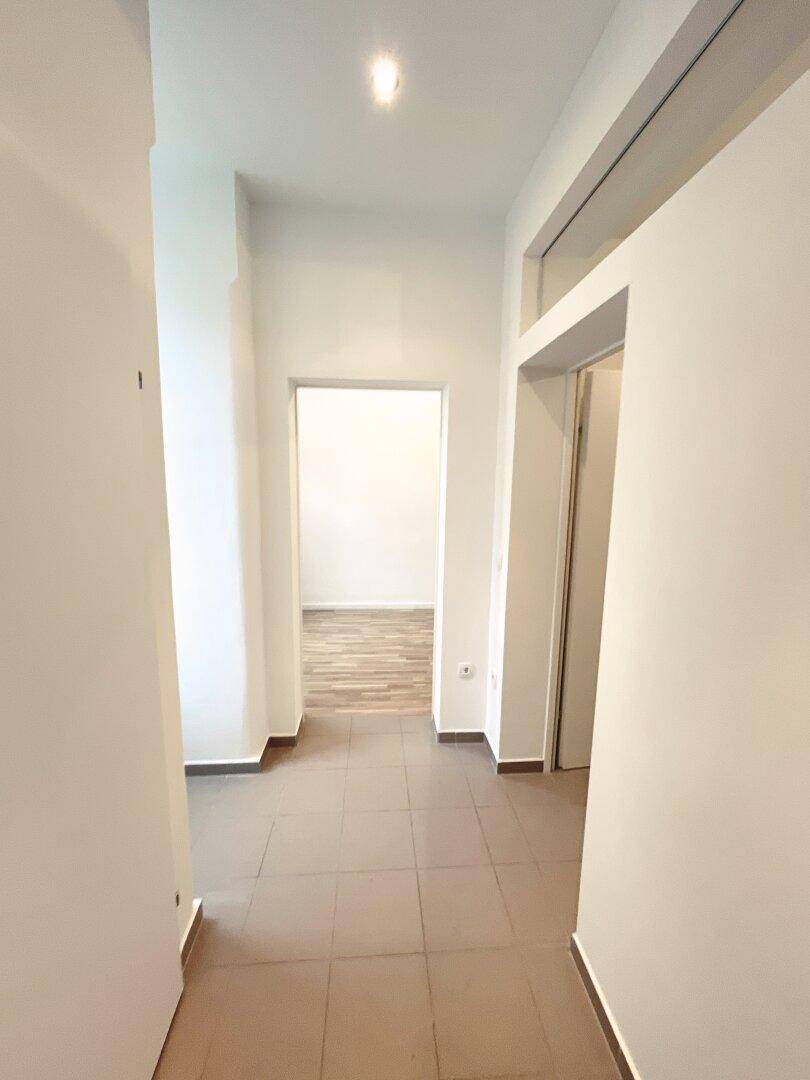 Langer, heller Flur mit Fliesenboden, der den Blick in weitere Zimmer freigibt.