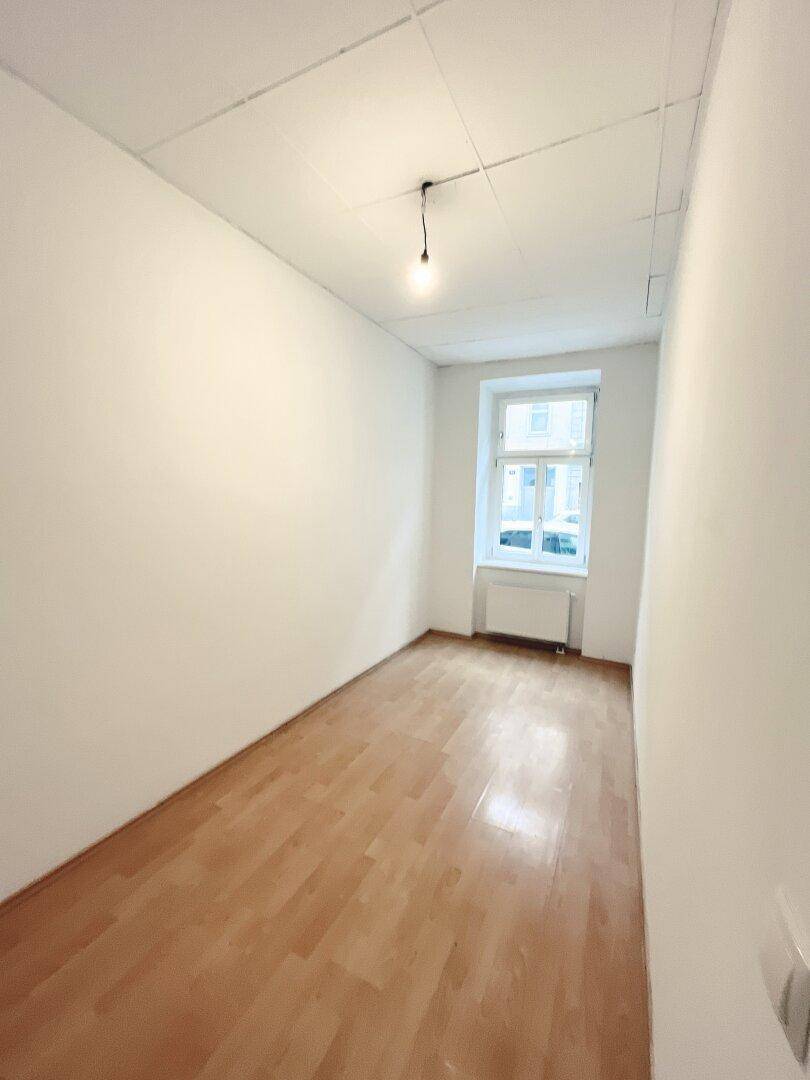 Schmaler, heller Raum mit Parkettboden und einem Fenster, ideal als Arbeits- oder Schlafzimmer.