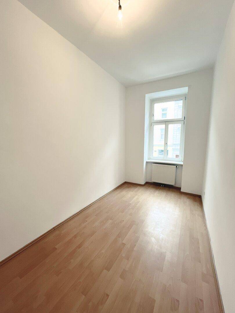Helles Zimmer mit Parkettboden und einem Fenster, bietet vielseitige Nutzungsmöglichkeiten.