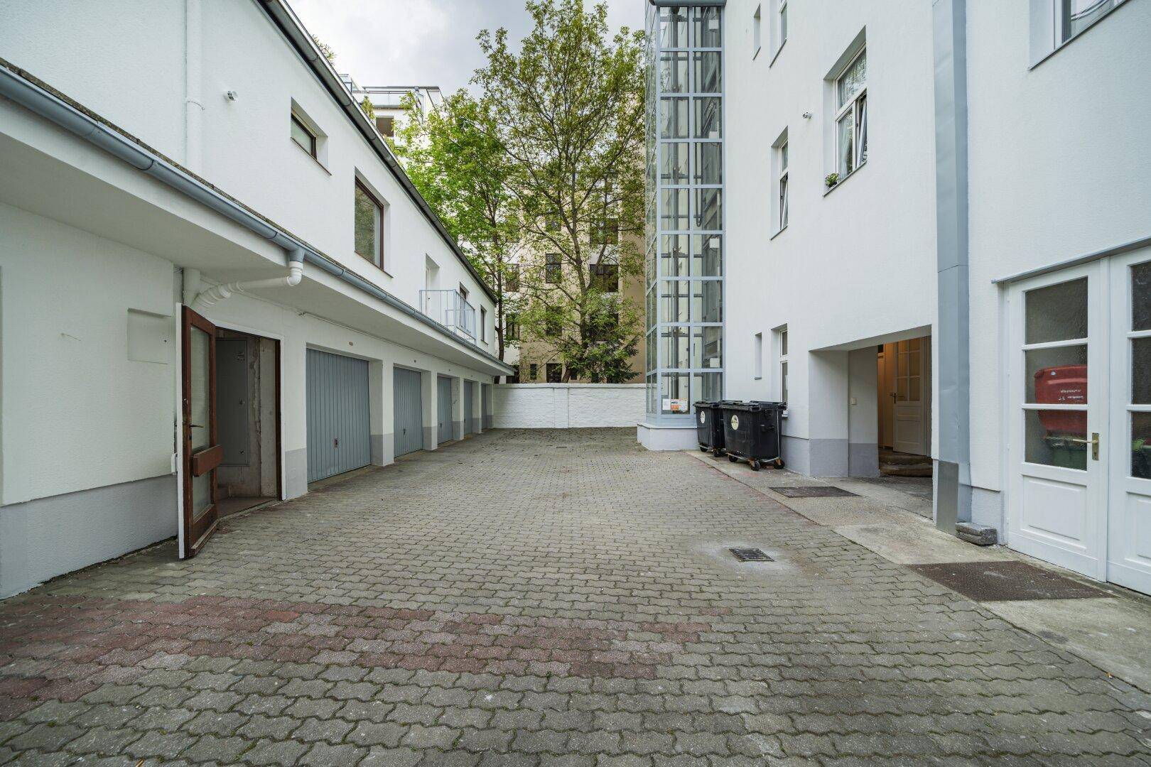 Innenhof mit Garagen und einem externen Glasaufzug, umgeben von Wohngebäuden.