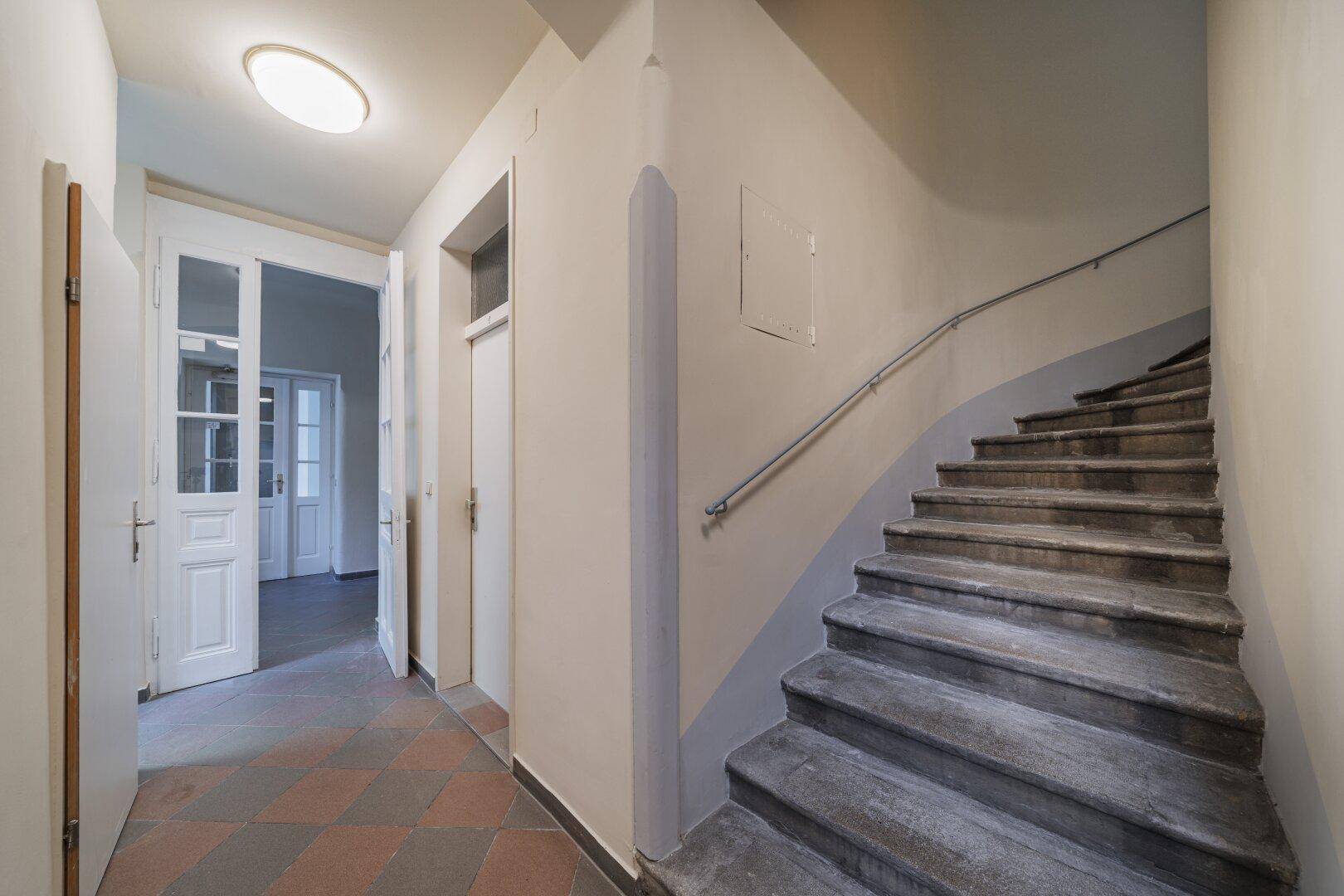 Treppenhaus mit Steinstufen und Handlauf, führt zu den oberen Etagen des Gebäudes.