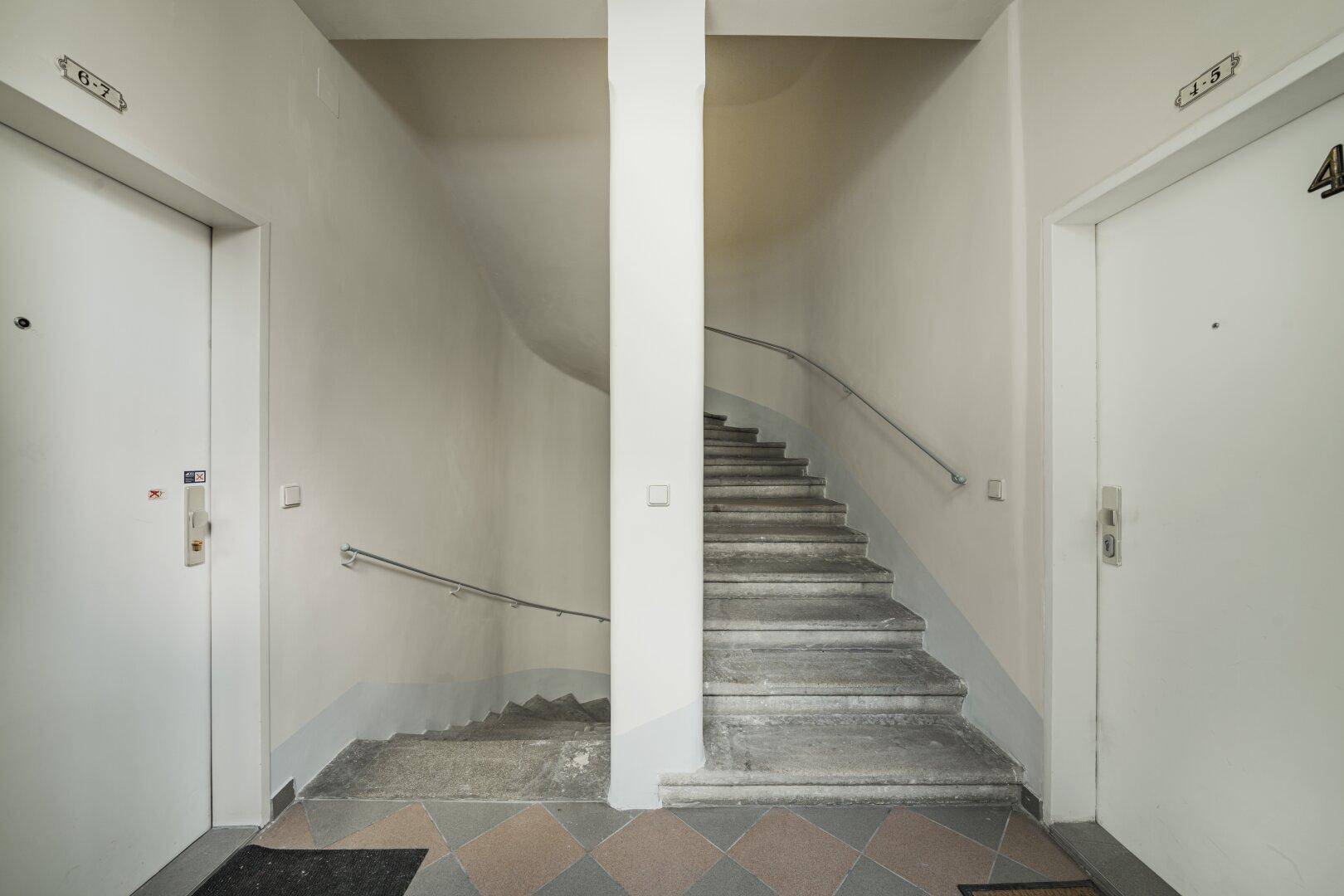 Gemeinschaftlicher Flur mit zwei Aufzügen und einem Treppenhaus, mit Fliesenboden.