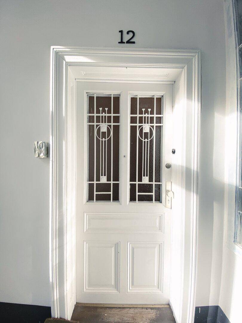 Elegante Eingangstür mit dekorativen Glaseinsätzen und der Hausnummer 12.