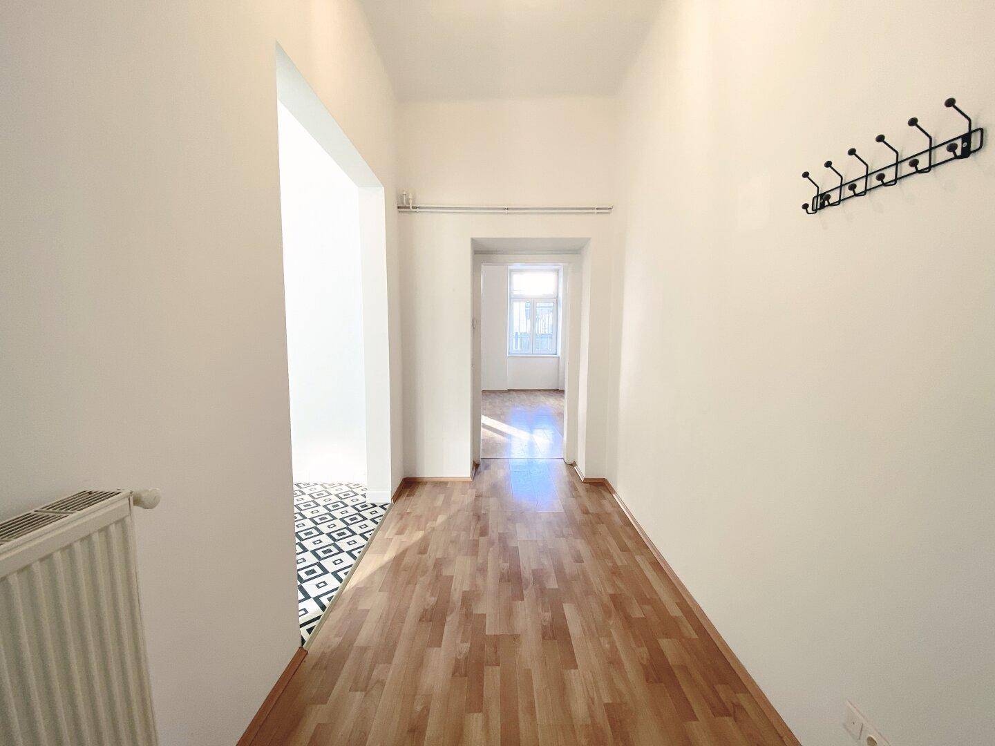 Langer Flur mit Holzfußboden, der verschiedene Räume der Wohnung miteinander verbindet.