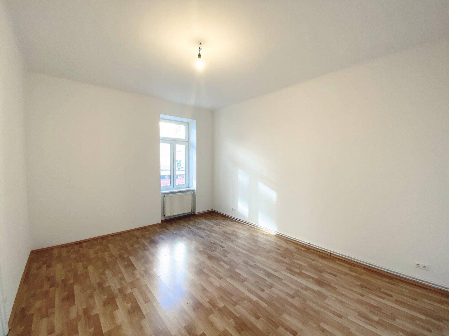 Ruhiges Zimmer mit Holzfußboden und einem Fenster, das eine angenehme Atmosphäre schafft.