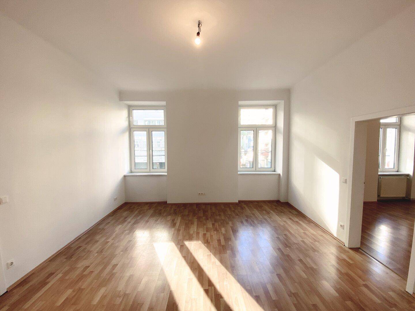 Heller Raum mit zwei Fenstern und Holzfußboden, bietet viel Potenzial für individuelle Gestaltung.