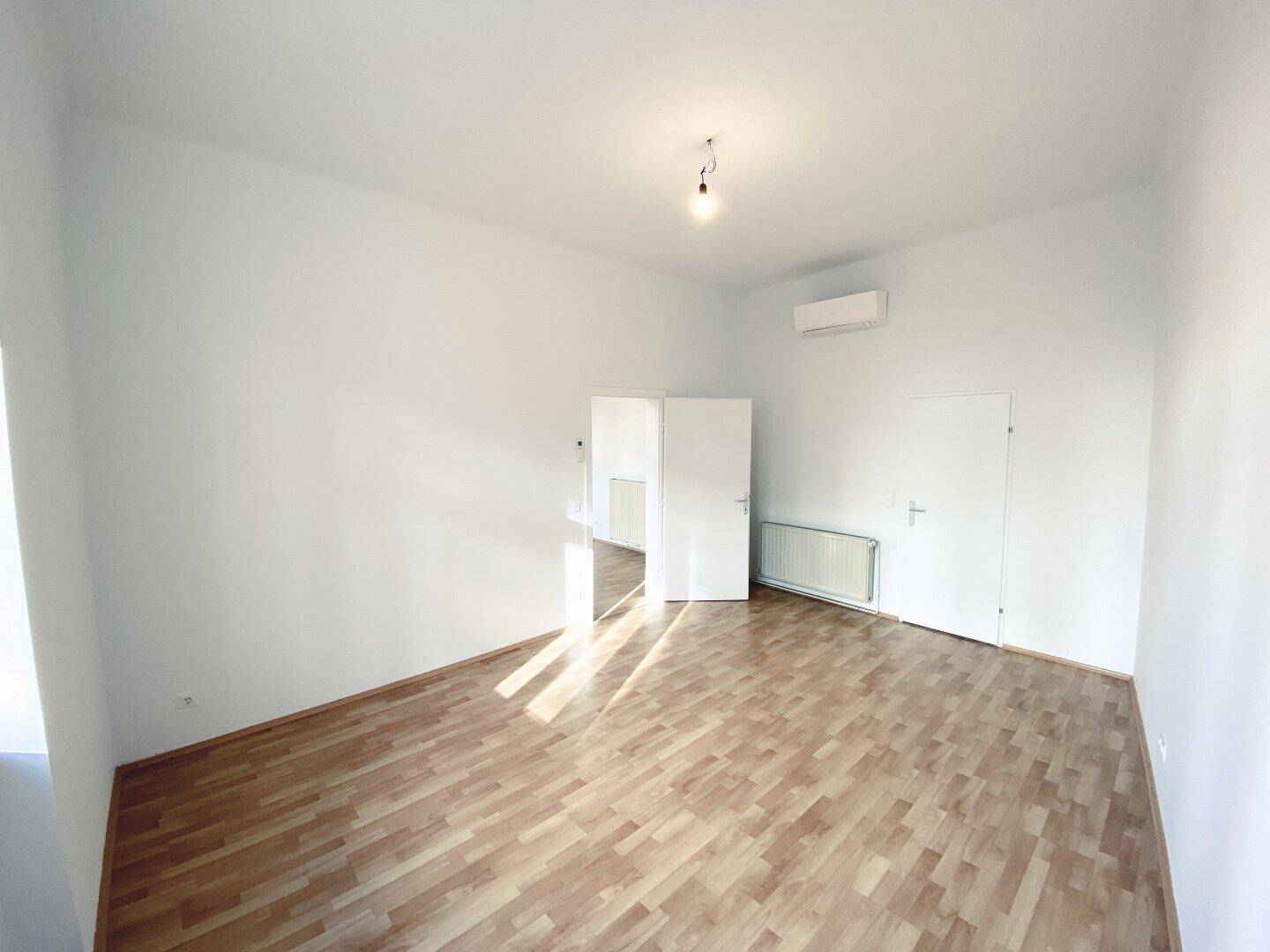 Geräumiges Zimmer mit Parkettboden und Klimaanlage, ideal für flexible Nutzung.